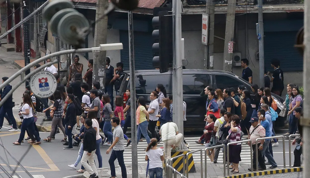 Pegawai keluar dari bangunan setelah gempa melanda Manila, Filipina (11/8). Akibat gempa tersebut istana Malacanang tempat Presiden Rodrigo Duterte berkantor terpaksa dievakuasi. (AP Photo/Aaron Favila)
