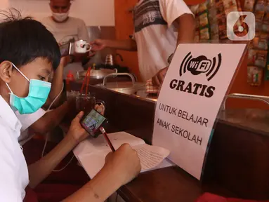 Seorang siswa sekolah dasar belajar dengan menggunakan wifi gratis yang disediakan oleh warkop Rizki, di Pondok Aren, Tangerang Selatan, Rabu (29/7/2020). Warung kopi tersebut menyediakan wifi gratis dan peminjaman laptop serta handphone. (Liputan6.com/Angga Yuniar)