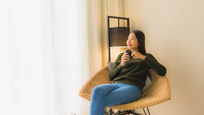 Seorang perempuan sedang menikmati secangkir kopi di sebuah kursi (Foto Dok: Freepik/lifeforstock)