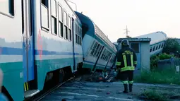 Petugas berjalan dekat rangkaian kereta api yang mengalami kecelakaan dan keluar jalur di dekat Turin, Italia, Kamis (24/5). Kecelakaan terjadi ketika rangkaian kereta api menghantam truk besar yang berhenti di sebuah perlintasan. (AP/Antonio Calanni)