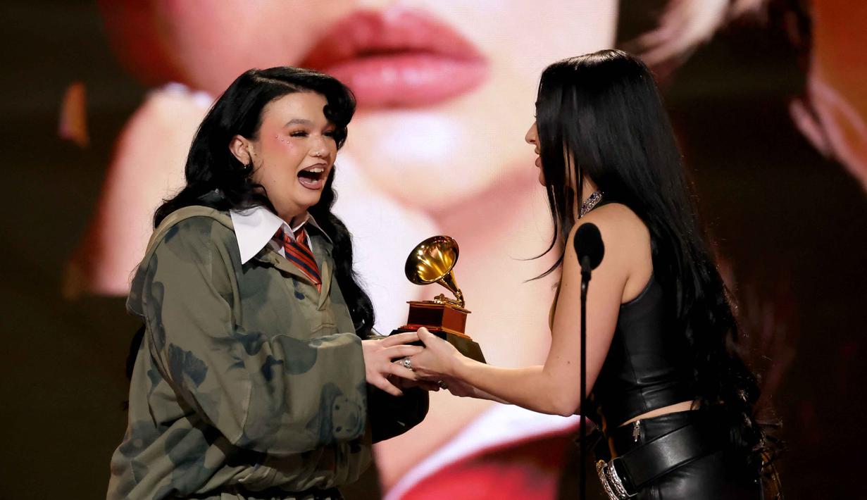 Penyanyi sekaligus penulis lagu asal Inggris, Lola Young (kiri) menerima penghargaan untuk kategori Penyanyi Pop Terbaik dari Charli XCX di atas panggung Penghargaan GRAMMY ke-68 di Crypto.com Arena, Los Angeles, California, pada 1 Februari 2026. (KEVIN WINTER/GETTY IMAGES NORTH AMERICA/Getty Images via AFP)