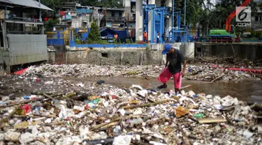 Petugas membersihkan sampah yang menyumbat Pintu Air Manggarai, Jakarta, Selasa (26/2). Meningkatnya debit air Sungai Ciliwung menyebabkan terjadi penumpukan sampah di Pintu Air Manggarai. (Liputan6.com/Faizal Fanani)