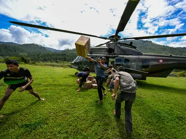 Warga membawa bantuan yang didistribusikan oleh personel TNI AU di wilayah terdampak banjir di Kabupaten Bener Meriah, Provinsi Aceh, pada Kamis 4 Desember 2025. Pendistribusian bantuan logistik bagi masyarakat terdampak banjir bandang di beberapa kabupaten di Aceh, terus dilakukan. (CHAIDEER MAHYUDDIN/AFP)