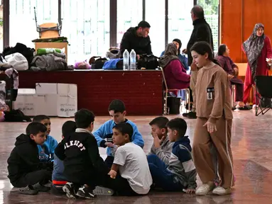 Anak-anak mengobrol sambil duduk di sebuah sekolah yang diubah menjadi tempat penampungan bagi pengungsi di kota Dekwaneh, utara Beirut, Lebanon, pada Kamis 5 Maret 2026. (Joseph EID/AFP)