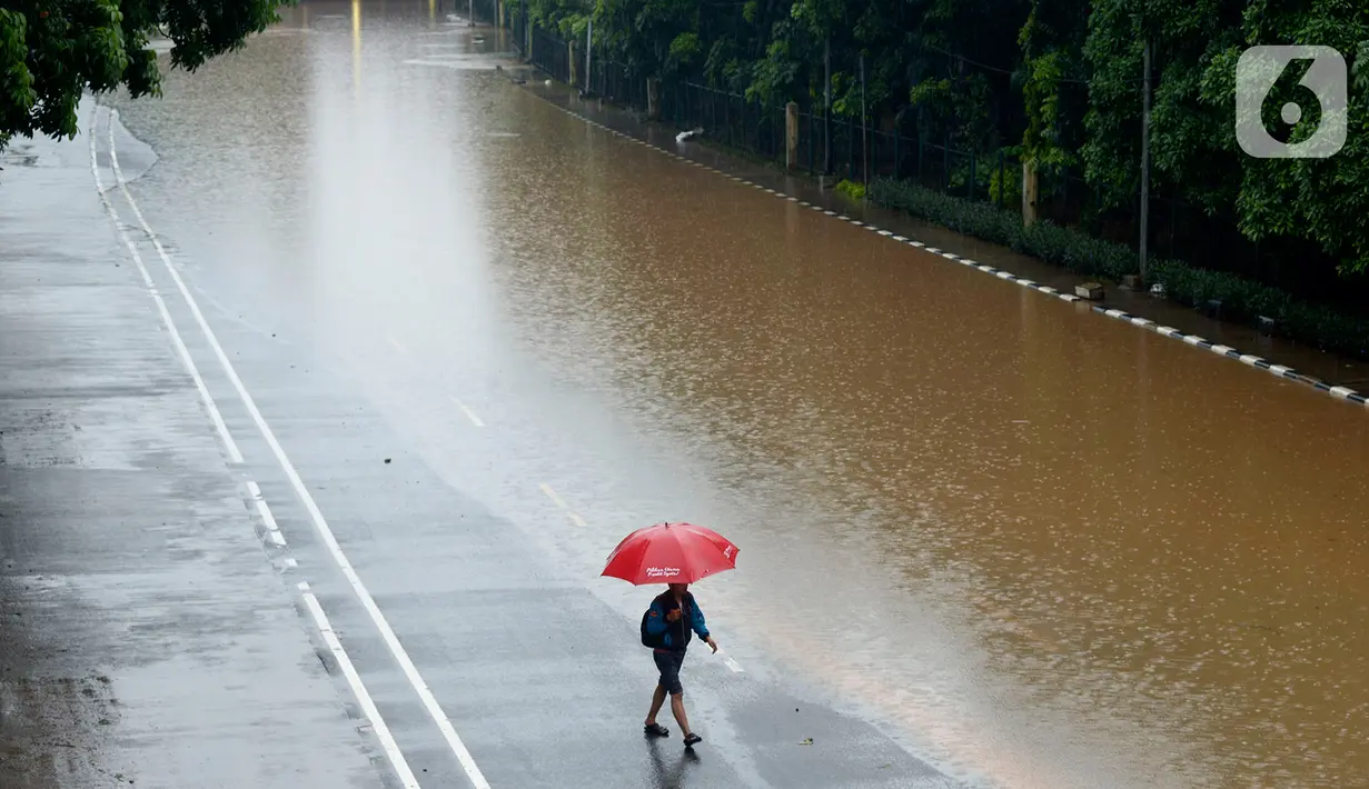 Warga berjalan melintasi kawasan Cawang-Uki, Jalan DI Panjaitan, Jakarta, Selasa (25/2/2020). Hujan yang mengguyur Jakarta sejak dini hari tadi membuat kawasan tersebut terendam banjir sekitar satu meter. (merdeka.com/Imam Buhori)