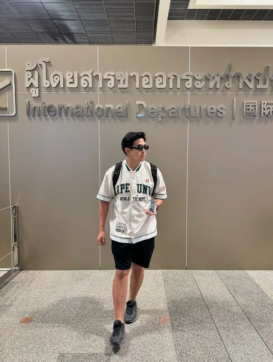 Outfit liburan ala Jerome Polin. Ia mengenakan atasan baseball shirt putih dan celana pendek hitam. Jerome menyempurnakan gayanya dengan tas backpack, sneakers abu-abu tua, dan sunglasses. [Foto: Instagram/jeromepolin]
