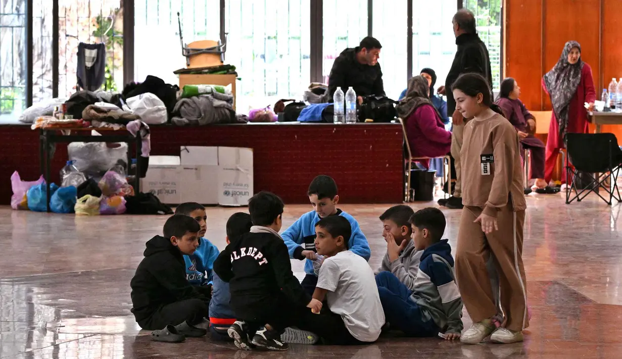 Anak-anak mengobrol sambil duduk di sebuah sekolah yang diubah menjadi tempat penampungan bagi pengungsi di kota Dekwaneh, utara Beirut, Lebanon, pada Kamis 5 Maret 2026. (Joseph EID/AFP)