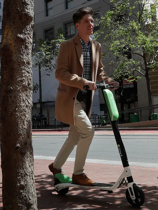 Seorang pria bernama Jack Handlery mengendarai skuter bermotor di jalanan di San Francisco (17/4). San Francisco menghentikan operasi perusahaan yang menyewakan skuter bermotor. (AP/Jeff Chiu)