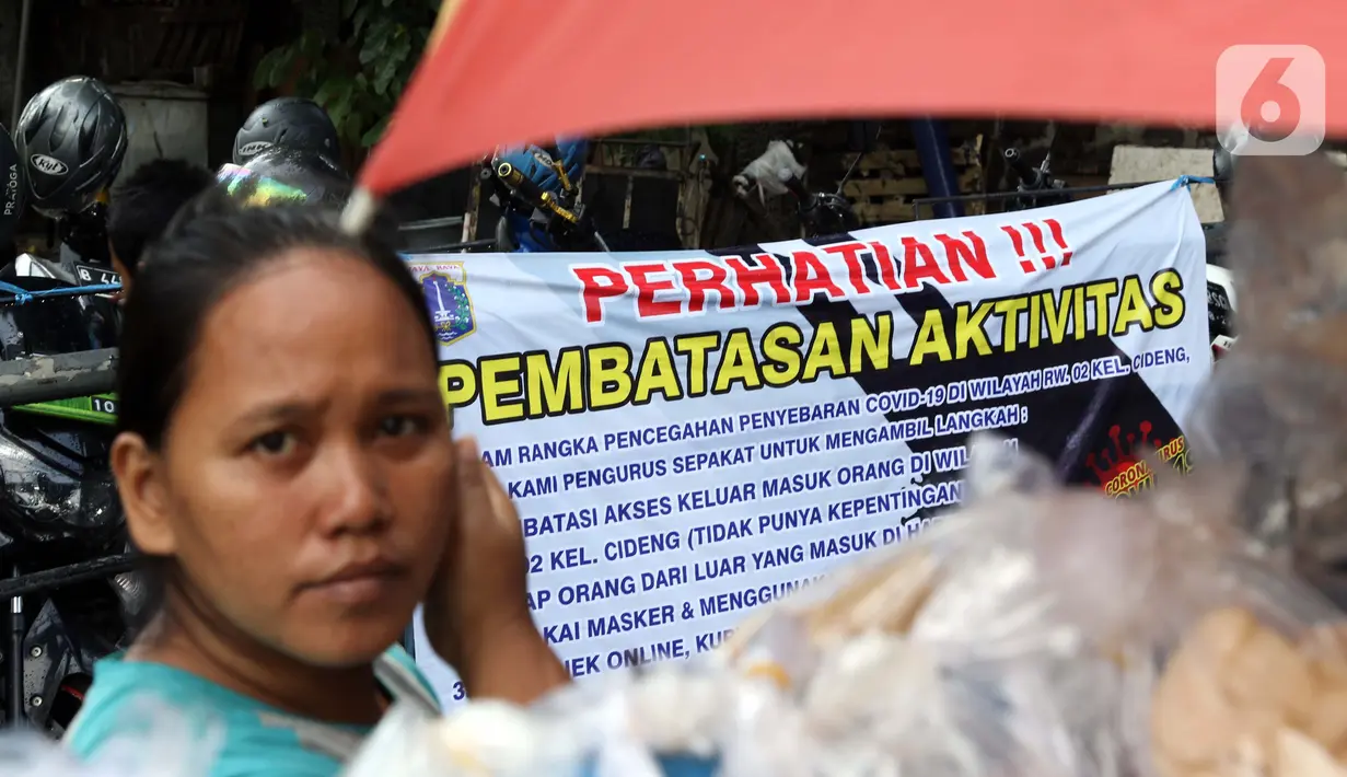 Warga beraktivitas di depan portal yang terpasang spanduk tentang pembatasan aktivitas di pintu masuk perumahan kawasan Cideng, Jakarta, Kamis (2/4/2020). Pemerintah menetapkan Pembatasan Sosial Berskala Besar (PSBB) di wilayah yang diduga terinfeksi COVID-19. (Liputan6.com/Helmi Fithriansyah)