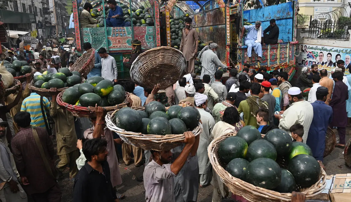Orang-orang berdagang semangka di pasar buah di Lahore, Pakistan (12/4/2022).  Semangka biasa dipanen buahnya untuk dimakan segar atau dibuat jus. (AFP/Arif Ali)
