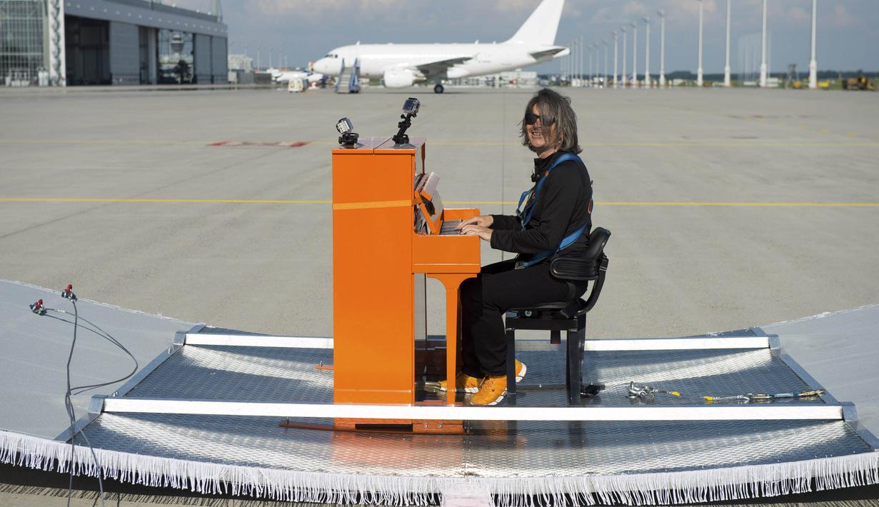 Pianis Jerman, Stefan Aaron berpose dengan piano oranye-nya di bandara Munich, Jerman, Rabu (23/7/14). (REUTERS/Lukas Barth) 