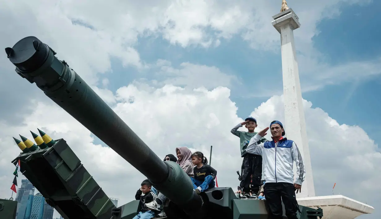 Pengunjung berfoto bersama peralatan militer yang dipamerkan selama Pameran Alat Utama Sistem Pertahanan (Alutsista) Tentara Nasional Indonesia (TNI) di Monumen Nasional (Monas) di Jakarta pada 21 September 2025. (YASUYOSHI CHIBA/AFP)