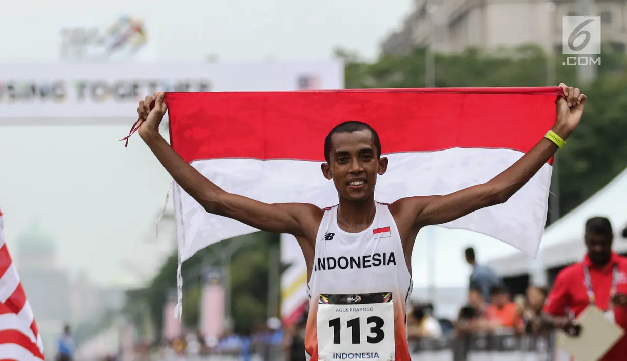 Pelari Indonesia Agus Prayogo membawa Bendera Merah Putih usai melakukan trek maraton SEA Games XXIX di di Putrajaya, Kuala Lumpur, Malaysia, Sabtu (19/8). Agus berhasil meraih medali perak nomor lari marathon cabang atletik. (Liputan6.com/Faizal Fanani)