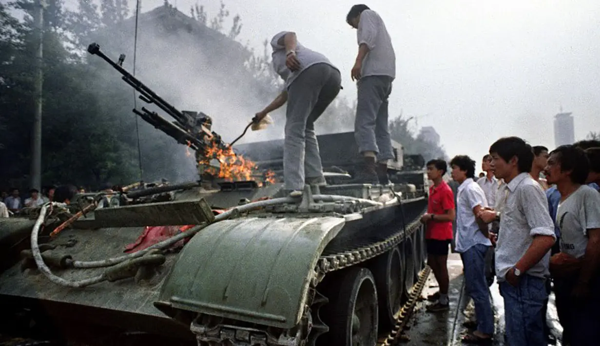 4 Juni 1989, beberapa warga memeriksa kendaraan lapis baja yang terbakar di dekat Lapangan Tiananmen, Tiongkok. (AFP PHOTO/TOMMY CHENG)