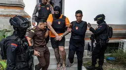 Tiga orang tersangka warga negara Australia yakni Tupou Pasa Midolmore, Coskun Mevlut, dan Darcy Francesco Jenson menjalani proses pelimpahan tahap II (tersangka dan barang bukti) dari penyidik Polres ke pihak Kejaksaan Negeri (Kejari) Badung, Bali pada 15 Oktober 2025. Tampak dalam foto, tersangka Tupou Pasa Midolmore (tengah) saat dibawa kembali ke rumah tahanan setelah menjalani pemeriksaan oleh pihak kejaksaan di Badung, Bali, pada 15 Oktober 2025. (Dicky Bisinglasi/AFP)
