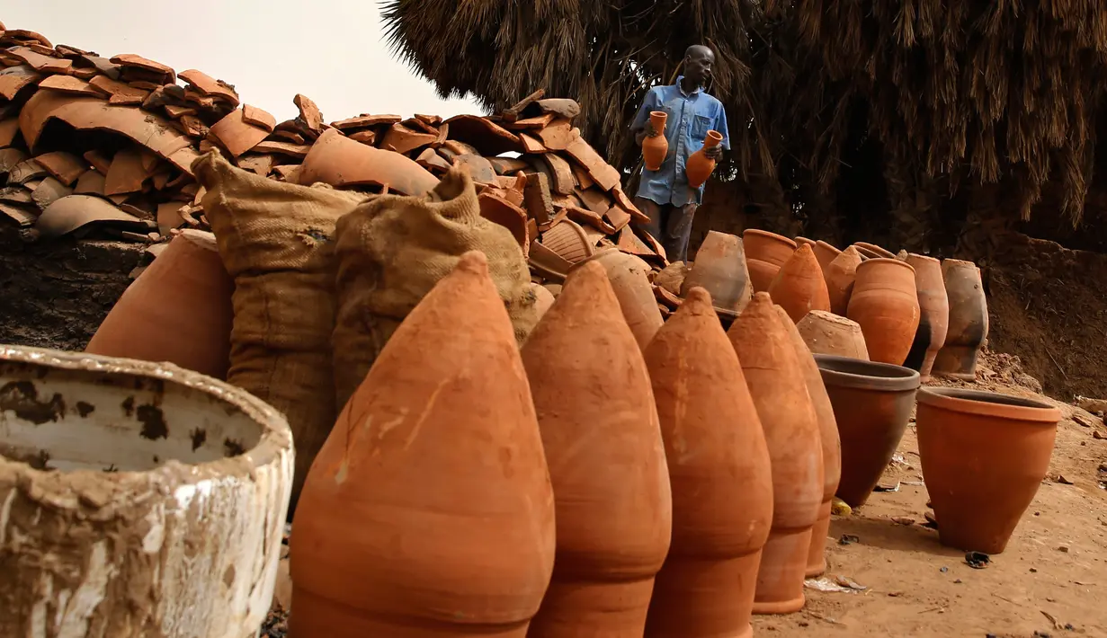 Pekerja menjemur pot tanah liat di sebuah bengkel tembikar di Khartoum, Sudan, Kamis (27/6/2019). Pot tanah liat tersebut nantinya akan dipajang untuk dijual. (AP Photo/Hussein Malla)