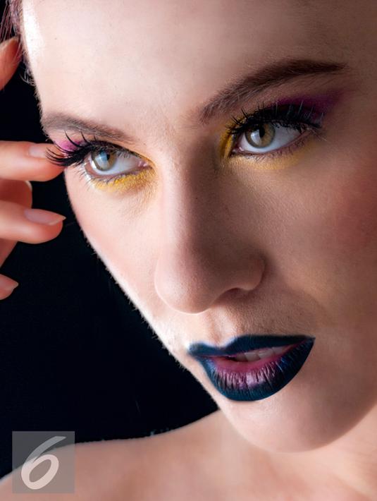 Teknik ombre alias memadukan 2 warna kontras pada riasan mata dan bibir juga dapat membuat tampilan jadi keren dan unik. Poleskan lipstik atau eyeshadow warna biru tua pada area bibir bagian luar dan sedikit bagian tengah. (Liputan6.com/Yudha Gunawan)