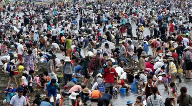 Sejumlah pengunjung menggali pasir untuk berburu kerang di pantai kawasan Yokohama, dekat Tokyo, Senin (30/4). Puluhan ribu orang berdesakan di pantai selama Golden Week atau periode liburan di Jepang pada akhir April hingga awal Mei. (AP/Koji Sasahara)