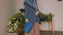 Cocok untuk outfit ke kantor, padukan tunik warna biru polos dengan rok plisket warna cokelat. Agar look makin stand out, bisa pilih hijab bermotif seperti potret ini! (Instagram/riamiranda).