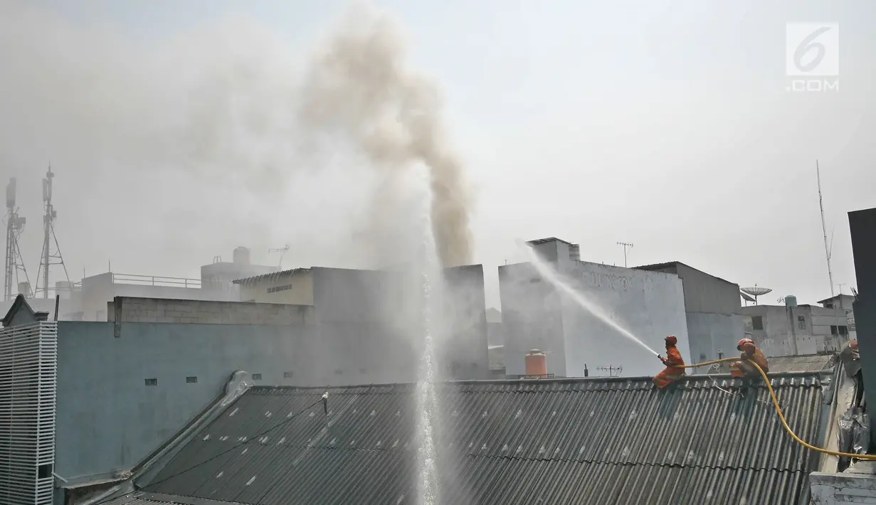 Petugas pemadam kebakaran berusaha memadamkan api yang membakar gudang petasan di jalan Asemka, Jakarta, Jumat (21/6/2019). Sebanyak 27 unit mobil dinas pemadam kebakaran dikerahkan untuk memadamkan gudang penyimpanan petasan itu. (Liputan6.com/Herman Zakharia)