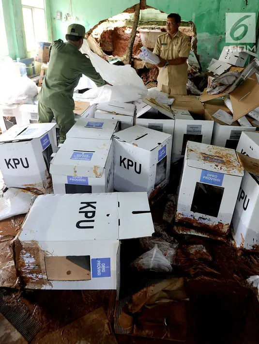 Petugas kecamatan menyelamatkan kotak suara kardus yang sebagian rusak terendam banjir di gudang tempat penyimpanan logistik di Kecamatan Ciseeng, Bogor, Senin (15/4). Lebih dari 600 kotak suara rusak akibat tembok gudang jebol diterpa hujan lebat dan angin kencang semalam. (merdeka.com/Arie Basuki)