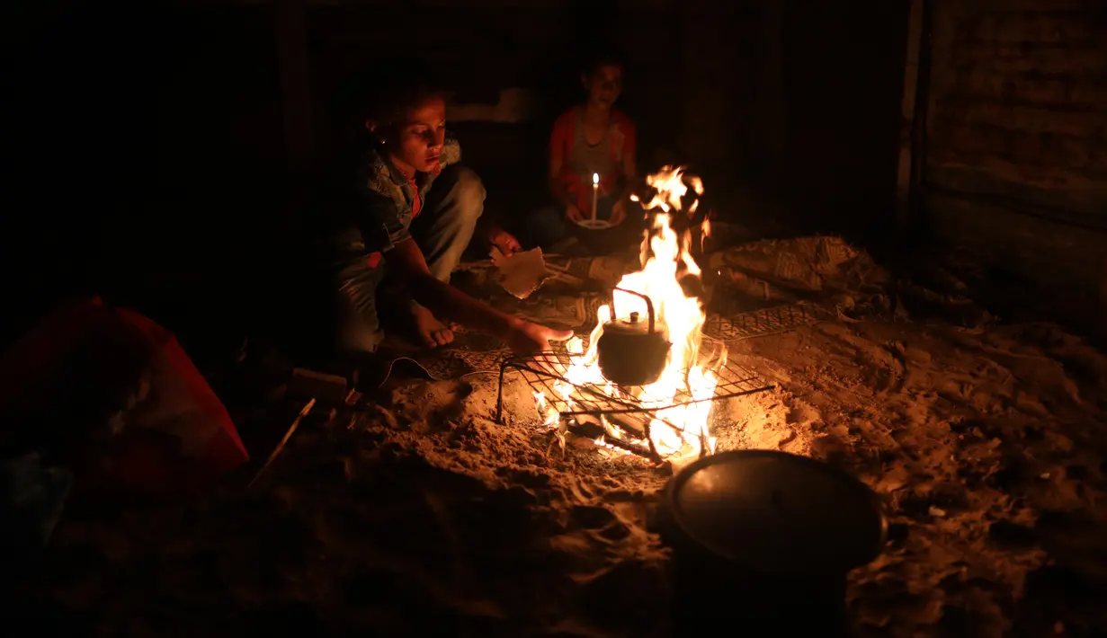 Warga Palestina duduk mengitari api unggun di luar rumah saat pemadaman listrik terjadi di Kota Khan Younis, Jalur Gaza selatan, pada 18 Agustus 2020. Satu-satunya pembangkit listrik di Jalur Gaza telah sepenuhnya berhenti beroperasi akibat kehabisan bahan bakar. (Xinhua/Yasser Qudih)