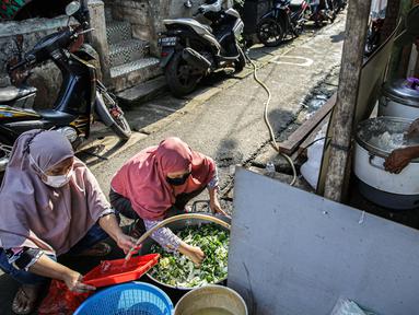 Warga menyiapkan bahan makanan untuk dibagikan di zona merah covid-19 Kelurahan Petogogan RT 006 RW 003, Jakarta, Selasa (22/6/2021). Dapur umum itu menyuplai kebutuhan makanan berat serta minuman untuk warga yang menjalani isolasi dan terdampak akibat COVID-19. (Liputann6.com/Faizal Fanani)