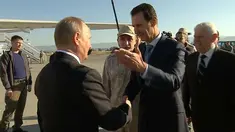 Presiden Suriah Bashar Assad bersalaman dengan Presiden Rusia, Vladimir Putin saat tiba di pangkalan udara Hemeimeem di Suriah (11/12). Putin menyatakan akan menarik pasukan Rusia di Suriah. (Presidential TV photo via AP)