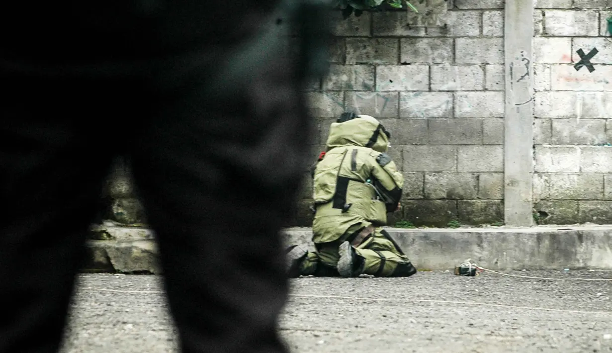 Dari hasil pemeriksaan tim penjinak bom Brimob Polda Jawa Barat, benda itu bukan bahan peledak, melainkan kayu. Tampak dalam foto, seorang petugas polisi dari unit penjinak bom memeriksa sebuah benda mencurigakan berbentuk kotak yang dibungkus lakban hitam dengan kabel di depan Gereja Kristen Protestan Simalungun (GKPS) di Bandung, Jawa Barat pada 19 Desember 2025. (Timur Matahari/AFP)