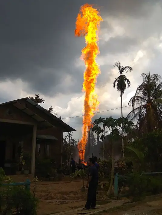 Orang-orang berusaha memadamkan sumur minyak ilegal milik warga yang terbakar di Peureulak, Provinsi Aceh, Rabu (25/4). Kebakaran sumur minyak tersebut menghaguskan tiga rumah penduduk dan dua lainnya rusak berat. (ILYAS ISMAIL/AFP)