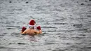 Anggota klub renang "Berliner Seehunde" (Berlin Seals) turun ke danau Orankesee sebagai bagian dari tradisi berenang pada Natal di Berlin, Jerman, Senin (25/12). Kegiatan ini salah satu tradisi di Berlin menyambut Natal setiap tahun. (AP/Markus Schreiber)