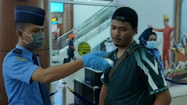 Seorang warga diperlihatkan petugas suhu tubuhnya setelah dites pakai alat sebagai langkah deteksi virus corona.