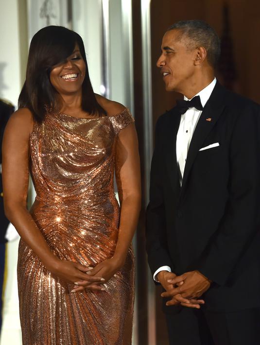Presiden AS Barack Obama dan Ibu Negara Michelle Obama  berbincang sambil menunggu kedatangan PM Italia Matteo Renzi di Gedung Putih, Washington, Selasa (18/10). Malam itu, Michelle tampil cantik berbalut gaun rancangan Versace. (Nicholas Kamm/AFP)