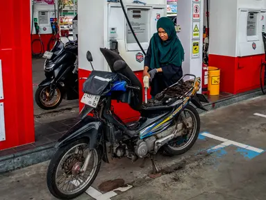 Seorang pengendara sepeda motor mengisi bahan bakar motornya di sebuah Stasiun Pengisian Bahan Bakar Umum (SPBU) yang dioperasikan oleh Pertamina, perusahaan minyak dan gas milik negara Indonesia, di Yogyakarta, pada Sabtu 28 Maret 2026. Konflik antara Iran dengan Amerika Serikat–Israel serta pembatasan di jalur strategis Selat Hormuz berdampak pada lonjakan harga minyak global. (DEVI RAHMAN/AFP)