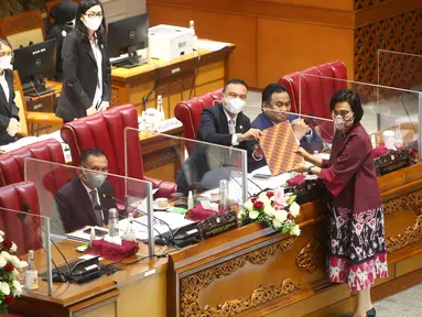 Pimpinan DPR menerima berkas tanggapan pemerintah dari Menteri Keuangan Sri Mulyani (kanan) saat rapat paripurna DPR Ke-10 masa Persidangan II Tahun Sidang 2021-2022 di Kompleks Parlemen, Senayan, Jakarta, Selasa (7/12/2021). (Liputan6.com/Angga Yuniar)