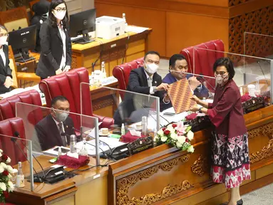 Pimpinan DPR menerima berkas tanggapan pemerintah dari Menteri Keuangan Sri Mulyani (kanan) saat rapat paripurna DPR Ke-10 masa Persidangan II Tahun Sidang 2021-2022 di Kompleks Parlemen, Senayan, Jakarta, Selasa (7/12/2021). (Liputan6.com/Angga Yuniar)