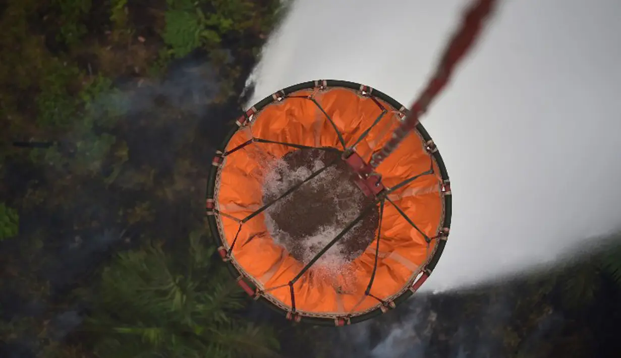 Air dilepaskan ke lahan yang terbakar oleh helikopter yang dioperasikan Basarnas di Pelalawan, Provinsi Riau, Kamis (17/9/2015). Asap dari kebakaran hutan ini mengakibatkan aktivitas warga Riau dan sekitarnya terganggu (AFP Photo/Adek Berry)