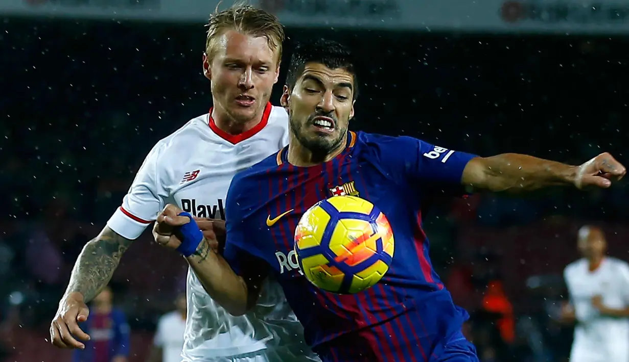 Penyerang Barcelona, Luis Suarez berusaha membawa bola dari kawalan pemain Sevilla, Simon Kjaer saat bertanding pada lanjutan La Liga Spanyol di Camp Nou, Barcelona, Spanyol, (4/11). Barcelona menang 2-1 atas Sevilla. (AP Photo/Manu Fernandez)