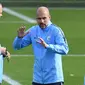 Pelatih Manchester City, Pep Guardiola (tengah) berbincang dengan asisten Mikel Arteta selama sesi pelatihan di City Football Academy, Inggris (18/9). City akan bertanding melawan wakil Prancis, Lyon pada grup F Liga Champions. (AFP Photo/Oli Scarff)