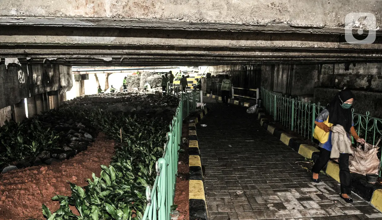 Warga berjalan melintasi taman yang sedang dibangun di kolong Jembatan Pegangsaan, Jakarta, Selasa (19/1/2021). Selain menjadi area interaksi warga sekitar, pembangunan taman di kolong jembatan tersebut untuk mempercantik kawasan bantaran kali. (merdeka.com/Iqbal S. Nugroho)