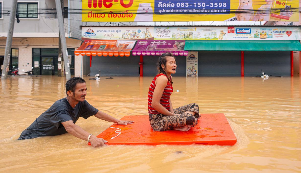 Sedikitnya, 33 orang tewas dan hampir dua juta penduduk dilaporkan terdampak, termasuk wisatawan yang terjebak di rumah serta hotel. Tampak dalam foto, seorang pria mengangkut seorang wanita melewati banjir di Hat Yai, Provinsi Songkhla, Thailand selatan, pada Rabu 26 November 2025. (Arnun Chonmahatrakool/THAI NEWS PIX/AFP)