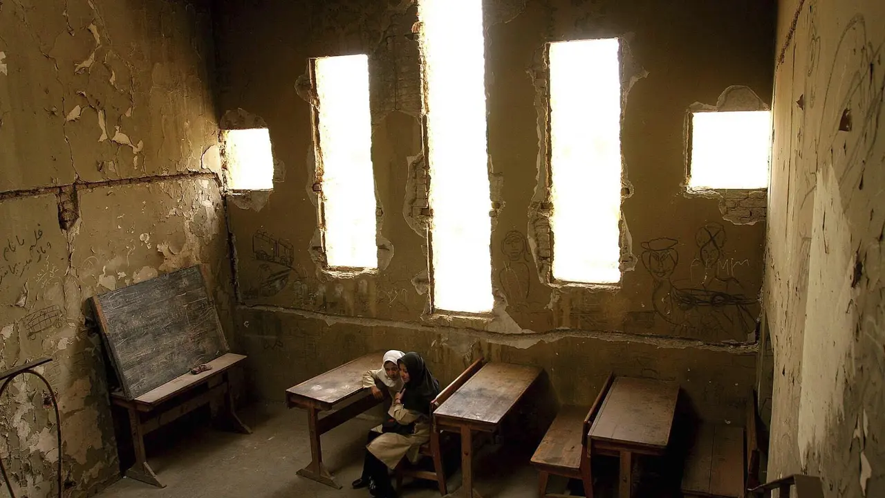 Basera, 13, kanan, dan Saira, 10, menunggu kelas mereka dimulai di sekolah Loy Ghar, di bangkai Teater Kabul yang dibom di ibukota Afghanistan, 20 April 2005 (AP Photo)