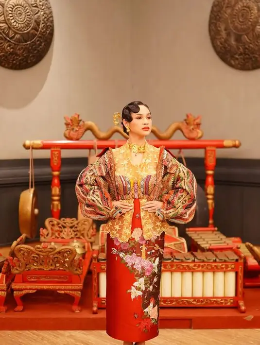 Andien tampil mengenakan kebaya brokat kuning dipadukan outer berupa bra top dan lengan balon, serta rok merah motif batik. [@hagaipakan]