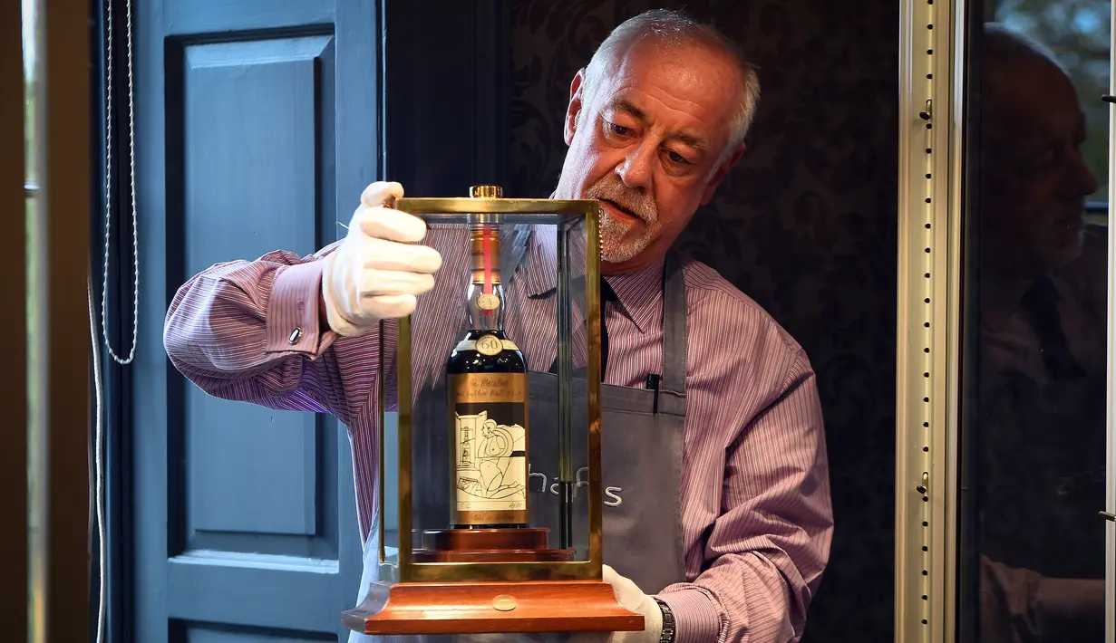 Seorang porter Bonhams menunjukkan botol wiski Macallan Valerio Adamai 1926 pada lelang di Edinburgh, Skotlandia, Rabu (3/10). Botol berusia 60 tahun itu menjadi botol wiski termahal di dunia setelah terjual seharga RP16,7 miliar. (AFP/Andy Buchanan)