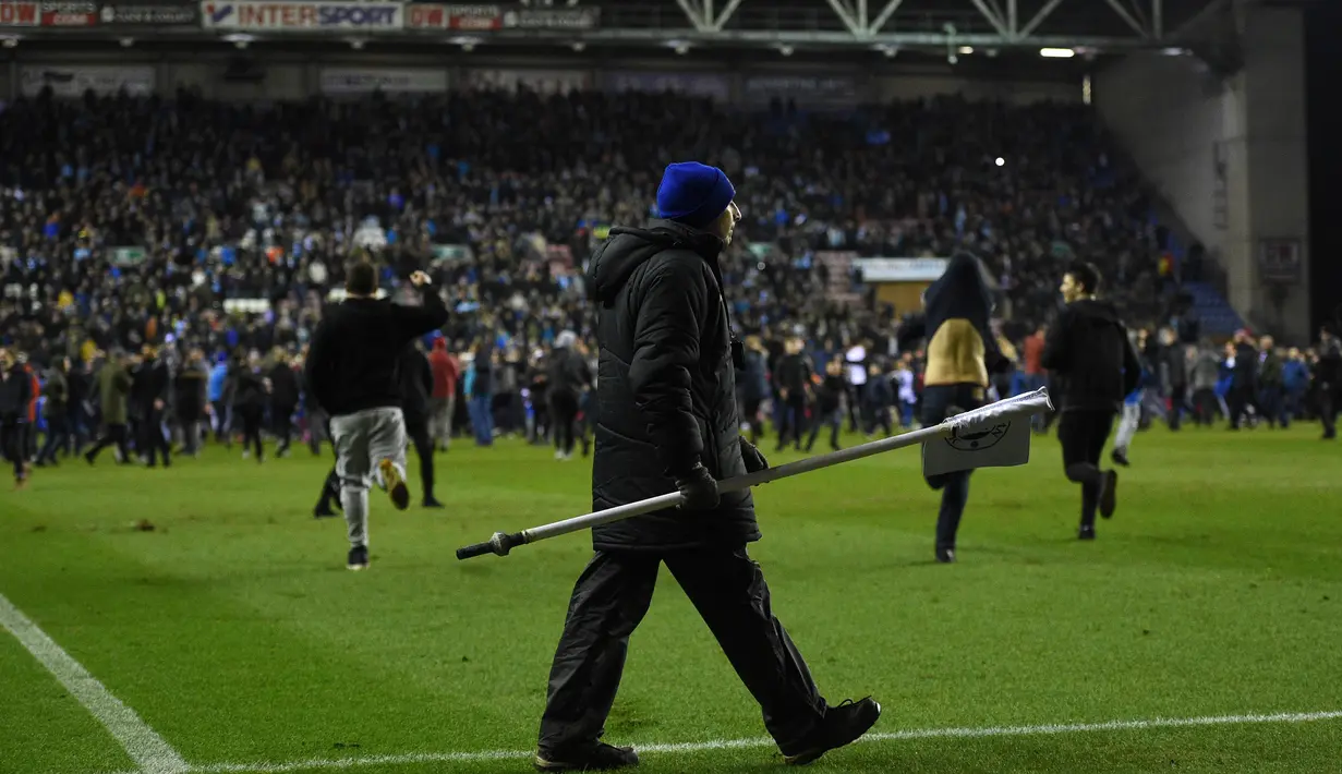 Keributan terjadi setelah Manchester City dikalahkan Wigan 0-1 pada babak kelima Piala FA di Stadion DW, Senin (19/2). Begitu peluit akhir dibunyikan wasit, suporter Manchester City tampak marah. (Oli SCARFF/AFP)