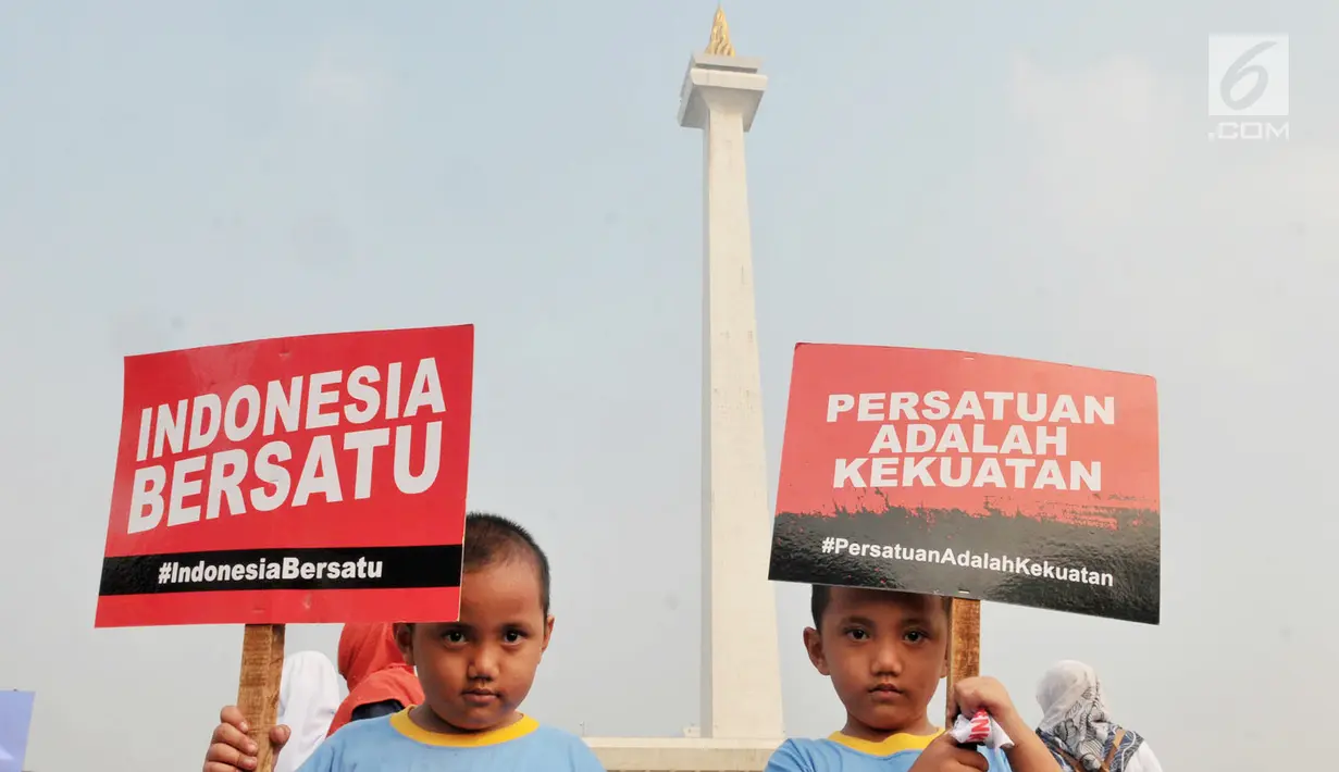 Dua anak kembar membawa poster saat mengikuti Festival Damai Millenial Road Safety di kawasan Monumen Nasional (Monas), Jakarta, Minggu (23/6). Festival ini juga dimeriahkan oleh berbagai atraksi dan pertunjukan musik artis Tanah Air. (merdeka.com/Iqbal Nugroho)