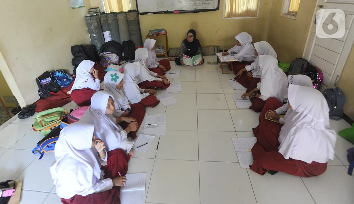 Aktivitas belajar mengajar siswa kelas VI  Madrasah Ibtidaiyah Mathlaul Anwar Ciangsana di lantai tanpa meja dan kursi pada bangunan majelis taklim, Tenjolaya, Kabupaten Bogor, Selasa(22/10/2019).  Kegiatan itu karena dua dari lima ruang kelas yang ada sudah rusak dan lapuk (merdeka.com/Arie Basuki)