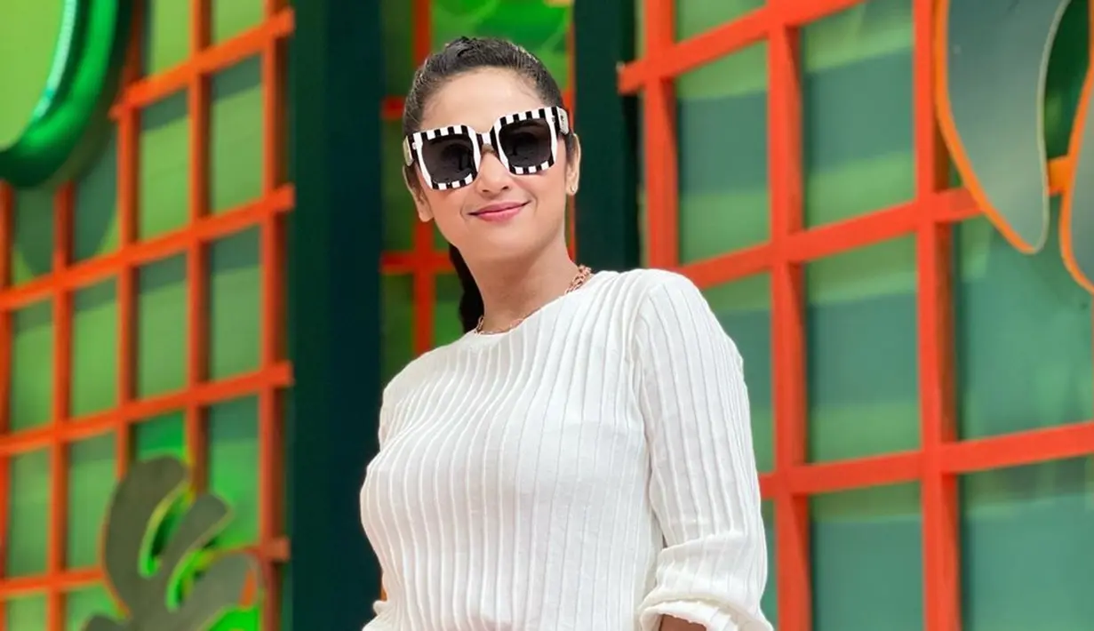 Tampil dengan busana berwarna putih, Dewi Perssik terlihat melengkapi penampilannya menggunakan kacamata hitam. Frame besar berwarna hitam putih pada kacamata ini pun menarik perhatian netizen. (Liputan6.com/IG/@dewiperssikreal.new)