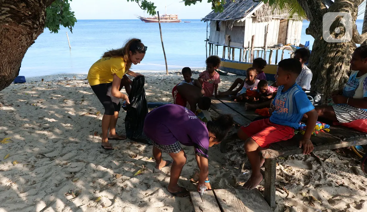 Aktivis AS, Carrie dan anak-anak membersihkan sampah plastik di bibir pantai Desa Sawandarek, Raja Ampat, Papua Barat (22/11/2019). Aksi membersihkan sampah plastik ini, digagas Carrie, aktivis asal Amerika Serikat,  yang sudah menetap di Indonesia selama 3 tahun. (Liputan6.com/Herman Zakharia)