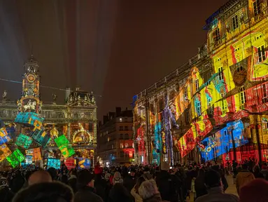 Orang-orang melihat balai kota Lyon (tengah) dan alun-alun Place des Terreaux yang diterangi cahaya lampu selama Festival of Lights (Fete des Lumieres) di kota Lyon, Prancis, Kamis (5/12/2019). Festival Cahaya ini merupakan salah satu kegiatan yang paling terkenal di Lyon. (ROMAIN LAFABREGUE / AFP)